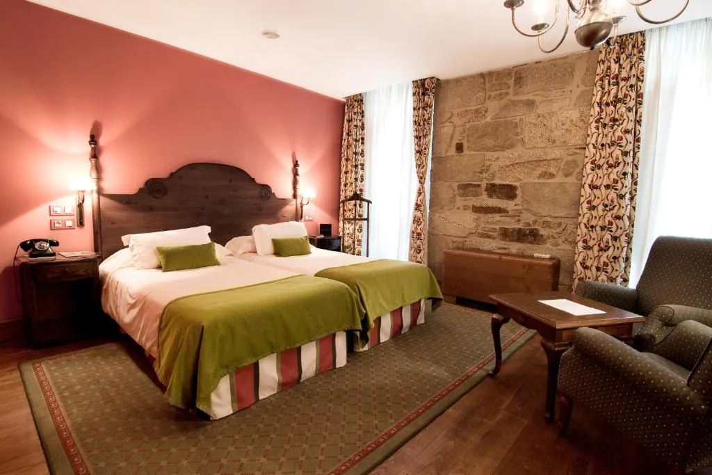 A comfortable twin room combining exposed Galician stone with traditional furnishings.