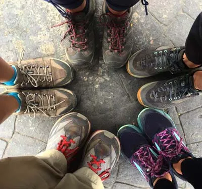 Five pairs of well-used walking shoes gathered in a circle.