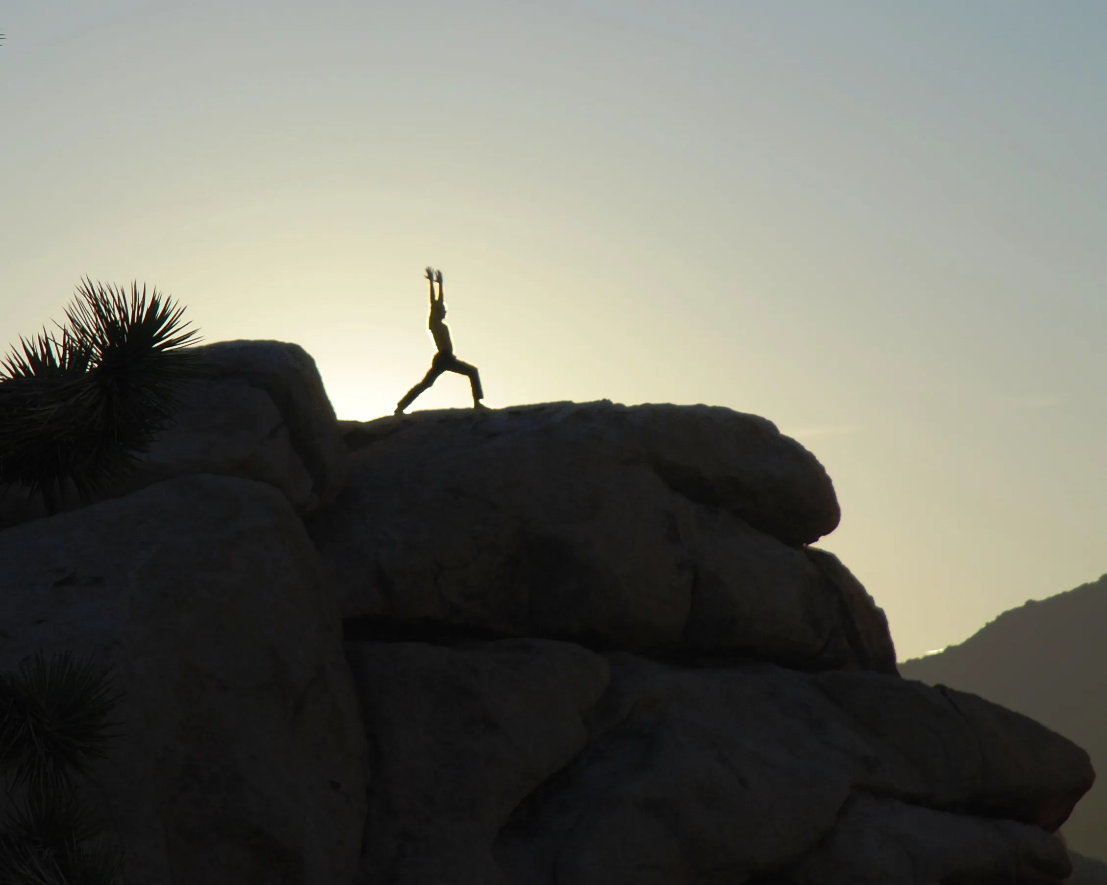 A traveler practising Warrior I outdoors at sunrise.