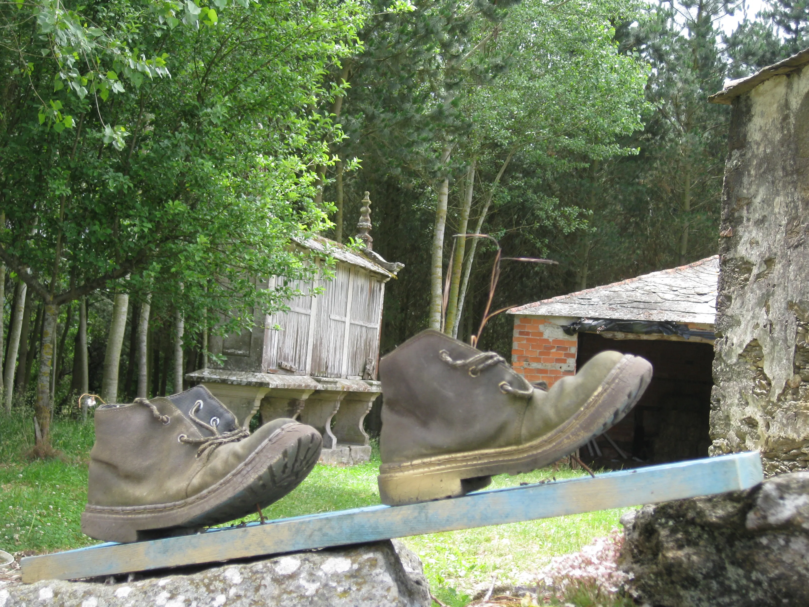 A pair of well-used walking boots beside a traditional Galician granary on the Camino.