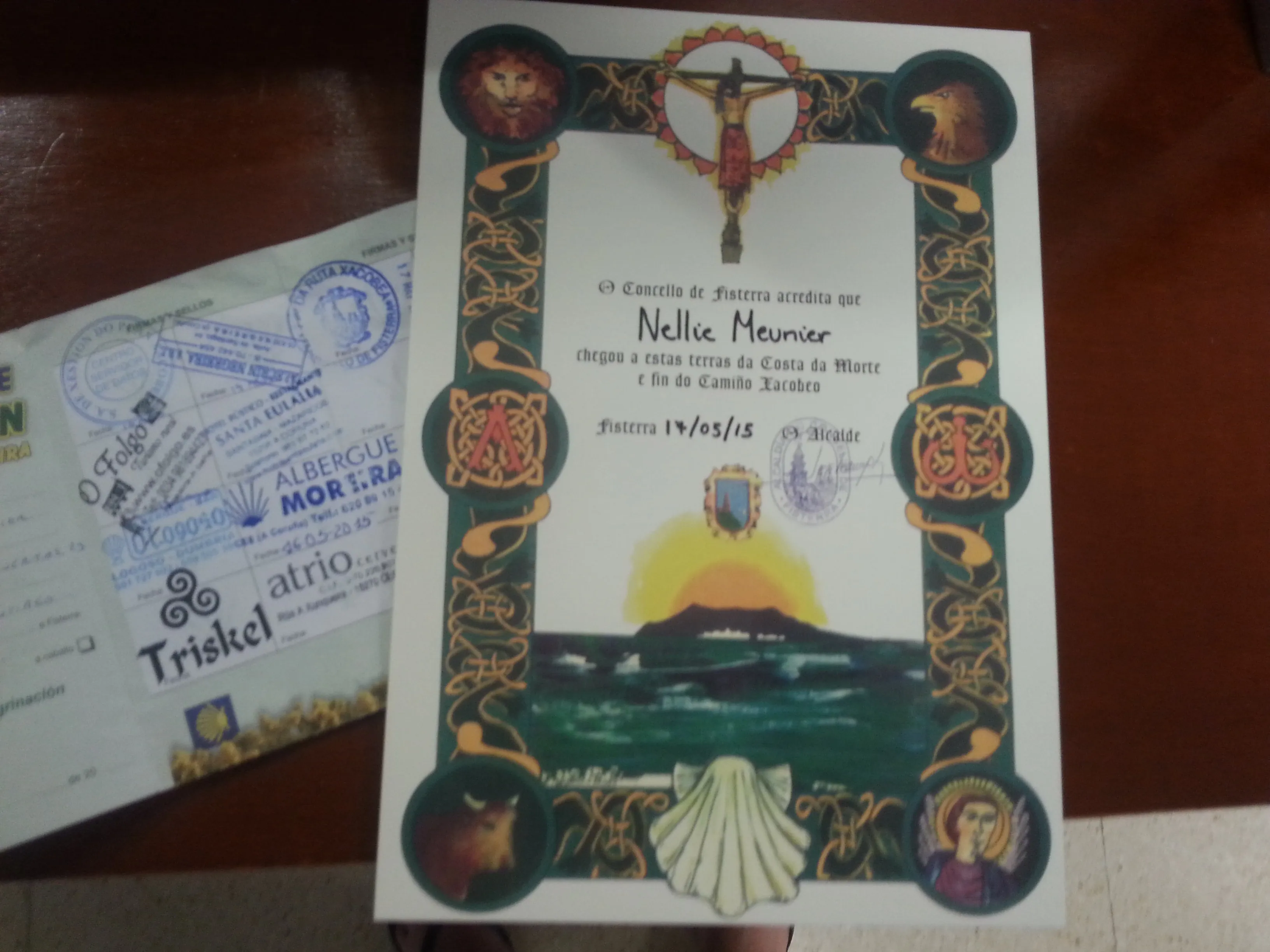 A personalized Fisterrana certificate displayed beside a stamped pilgrim credential.