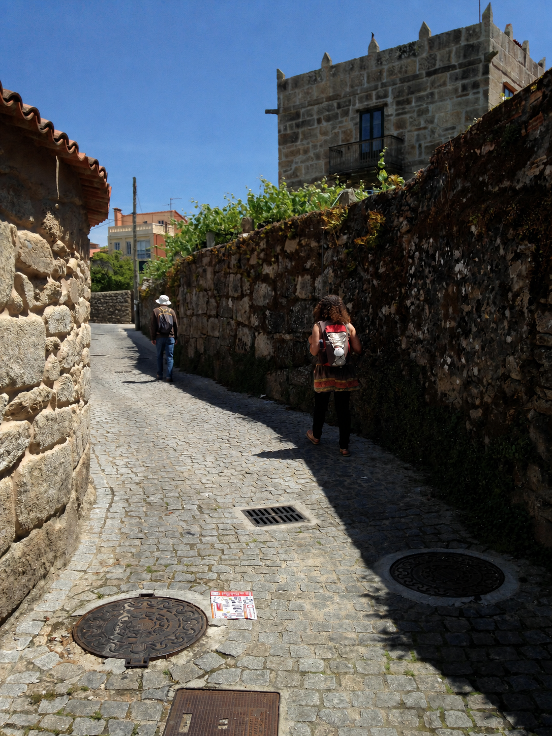 Dois caminhantes percorrem uma antiga trilha de pedras do Caminho.