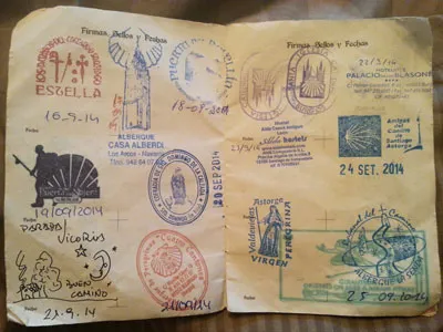 An open pilgrim credential filled with dated Camino stamps.