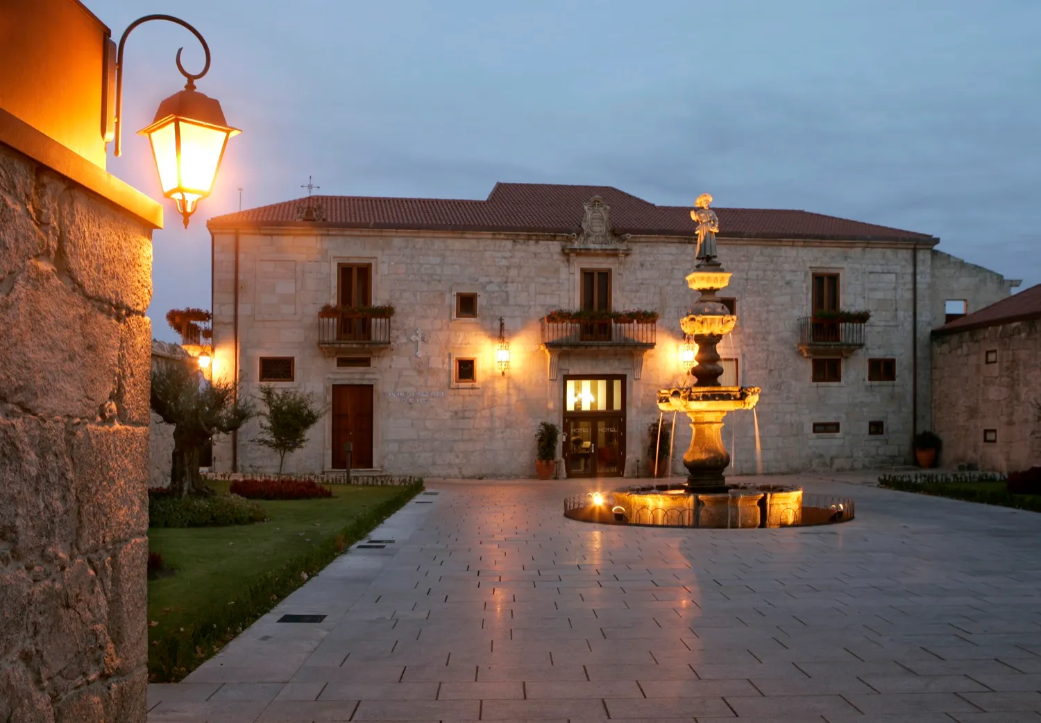 A historic Galician pazo illuminated around its courtyard at dusk.