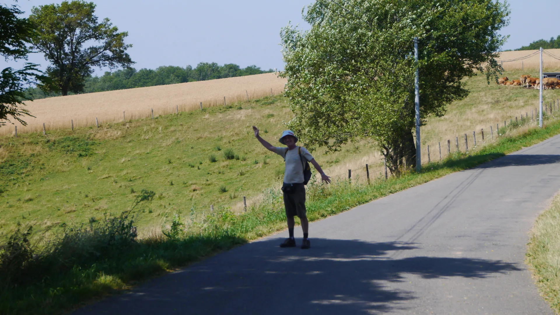A pilgrim greeting fellow walkers on a country road along the Camino.