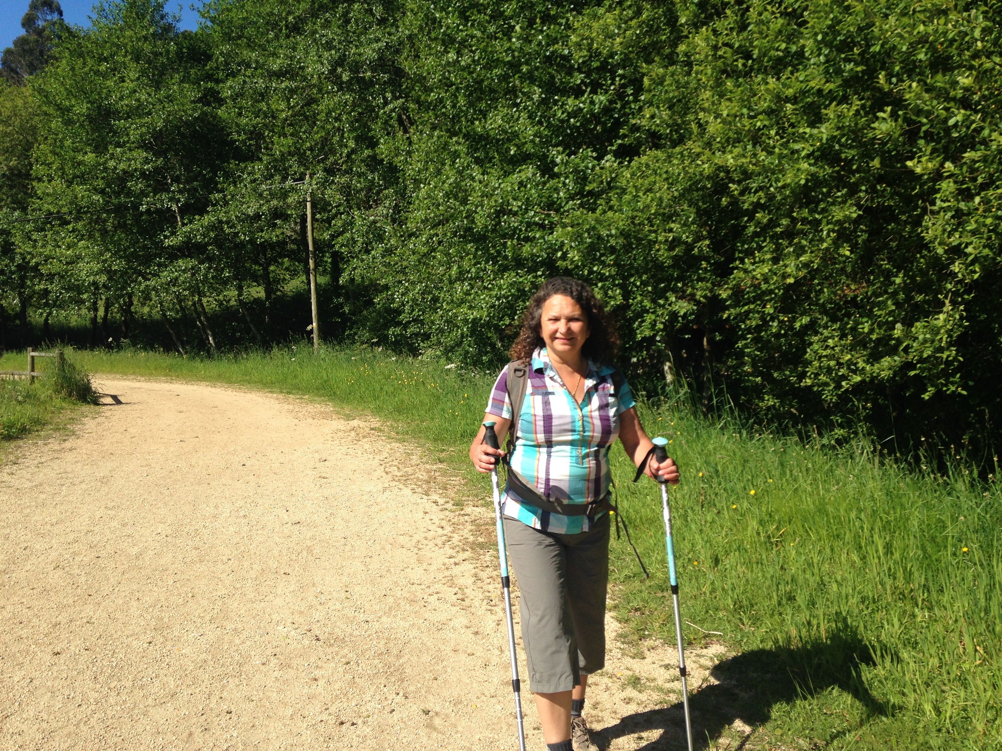 Uma peregrina percorre uma trilha arborizada do Caminho na Galícia.